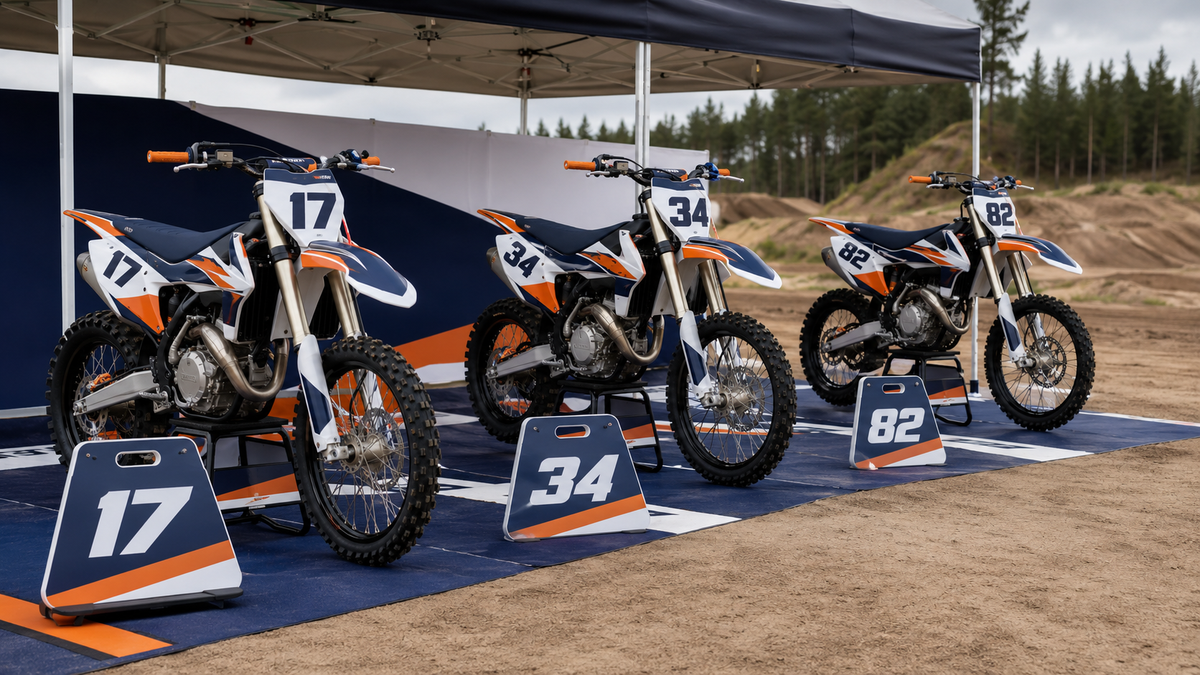 Kolme erikokoista motocross-pyörää yhtenäisellä sinivalkooranssilla tiimigrafiikalla