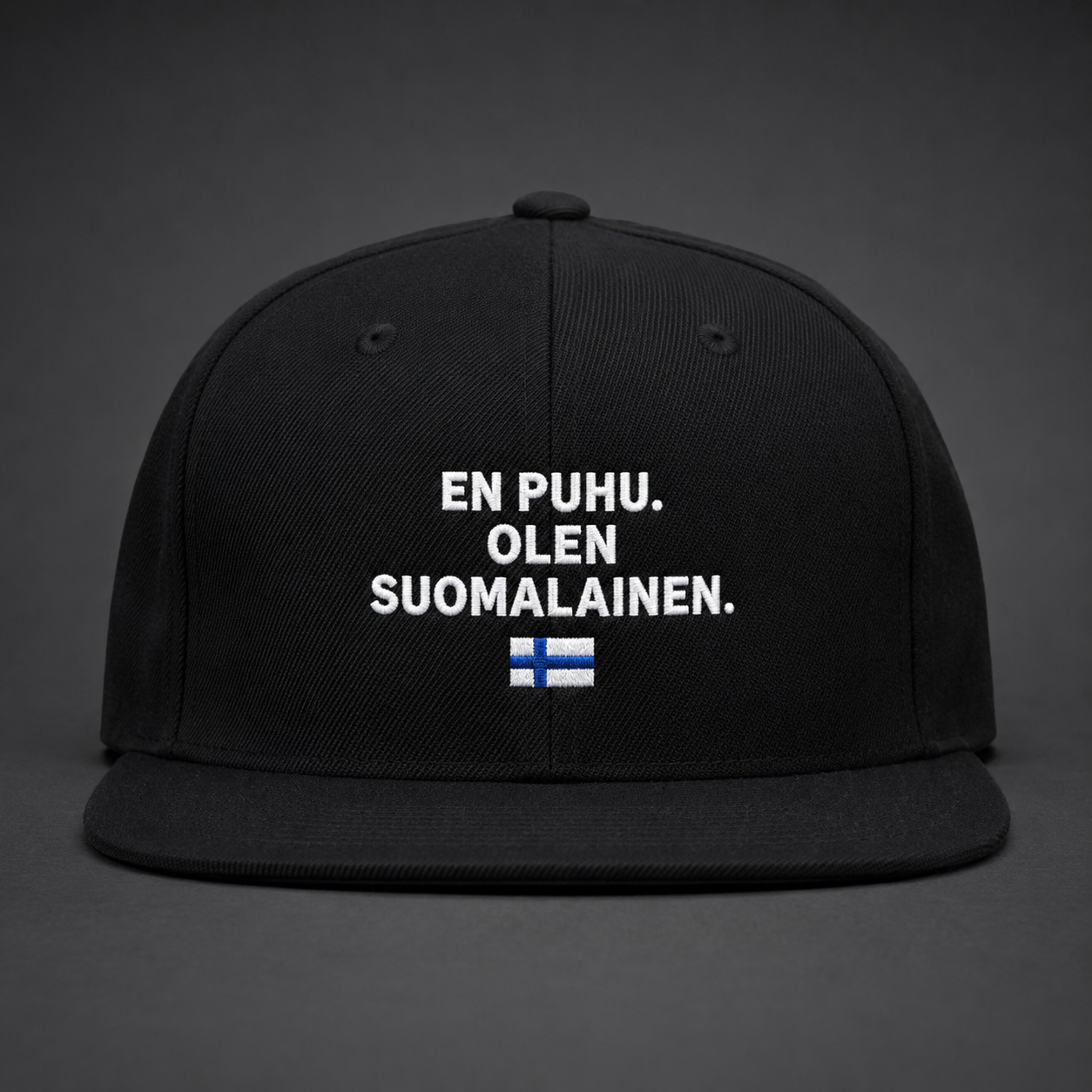 Musta suoralla lipalla varustettu lippis, jossa valkoinen EN PUHU. OLEN SUOMALAINEN. -kirjonta ja pieni Suomen lippu