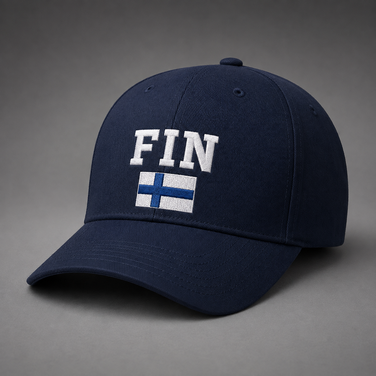 Tummansininen lippis, jossa suuret valkoiset FIN-kirjaimet ja brodeerattu Suomen lippu niiden alla.