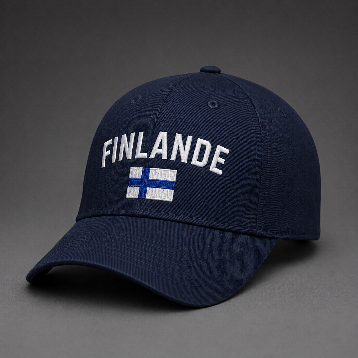 Tummansininen brodeerattu lippis, jossa suuri valkoinen FINLANDE-kaariteksti ja Suomen lippu.