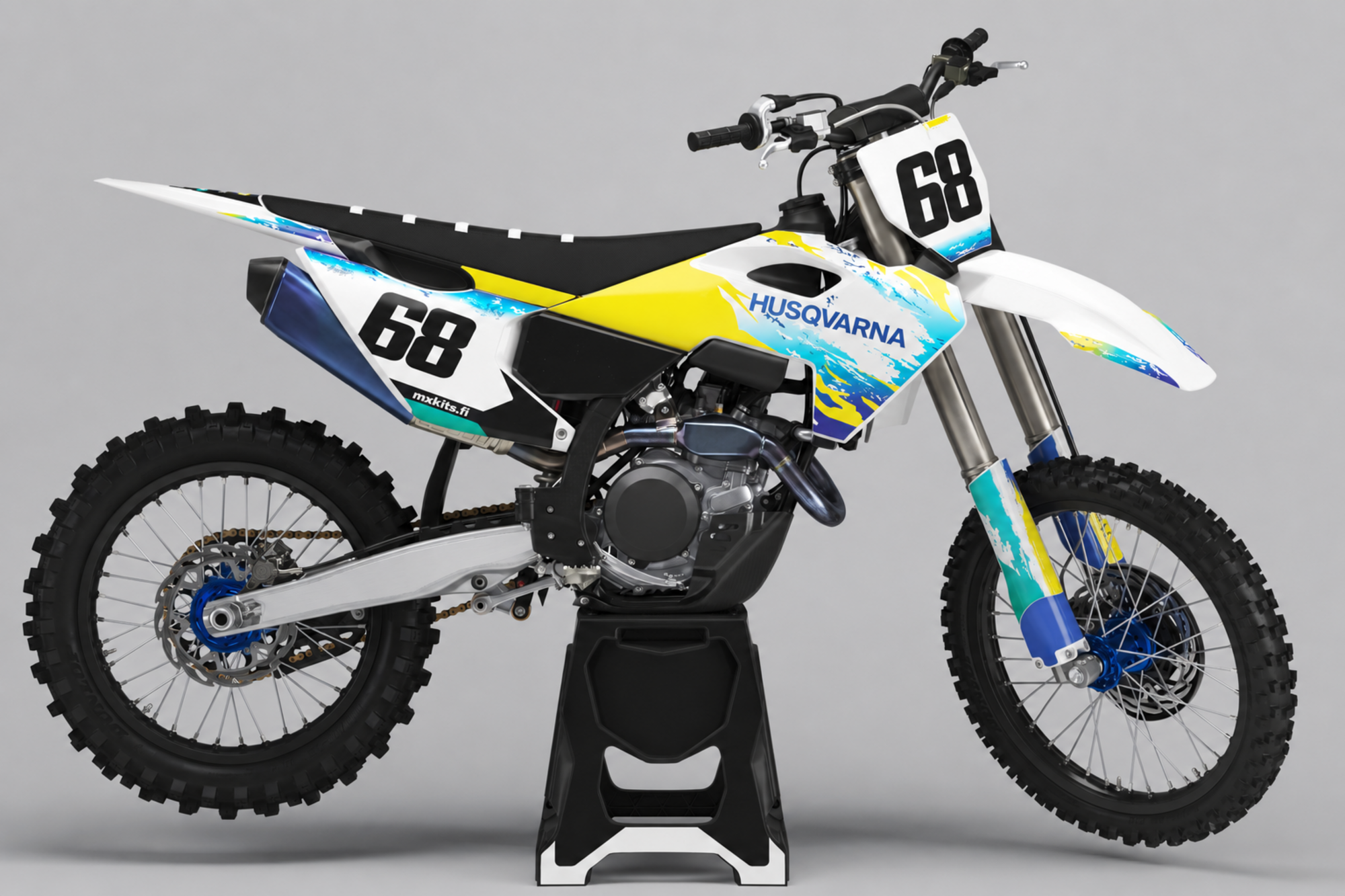 Valkoinen Husqvarna-motocrosspyörä kirkkaankeltaisella kiilalla sekä syaanilla, turkoosilla ja syvänsinisellä roiskegrafiikalla, mustat numerot 68 edessä ja vasemmalla sivulla, sininen HUSQVARNA ja valkoinen mxkits.fi.