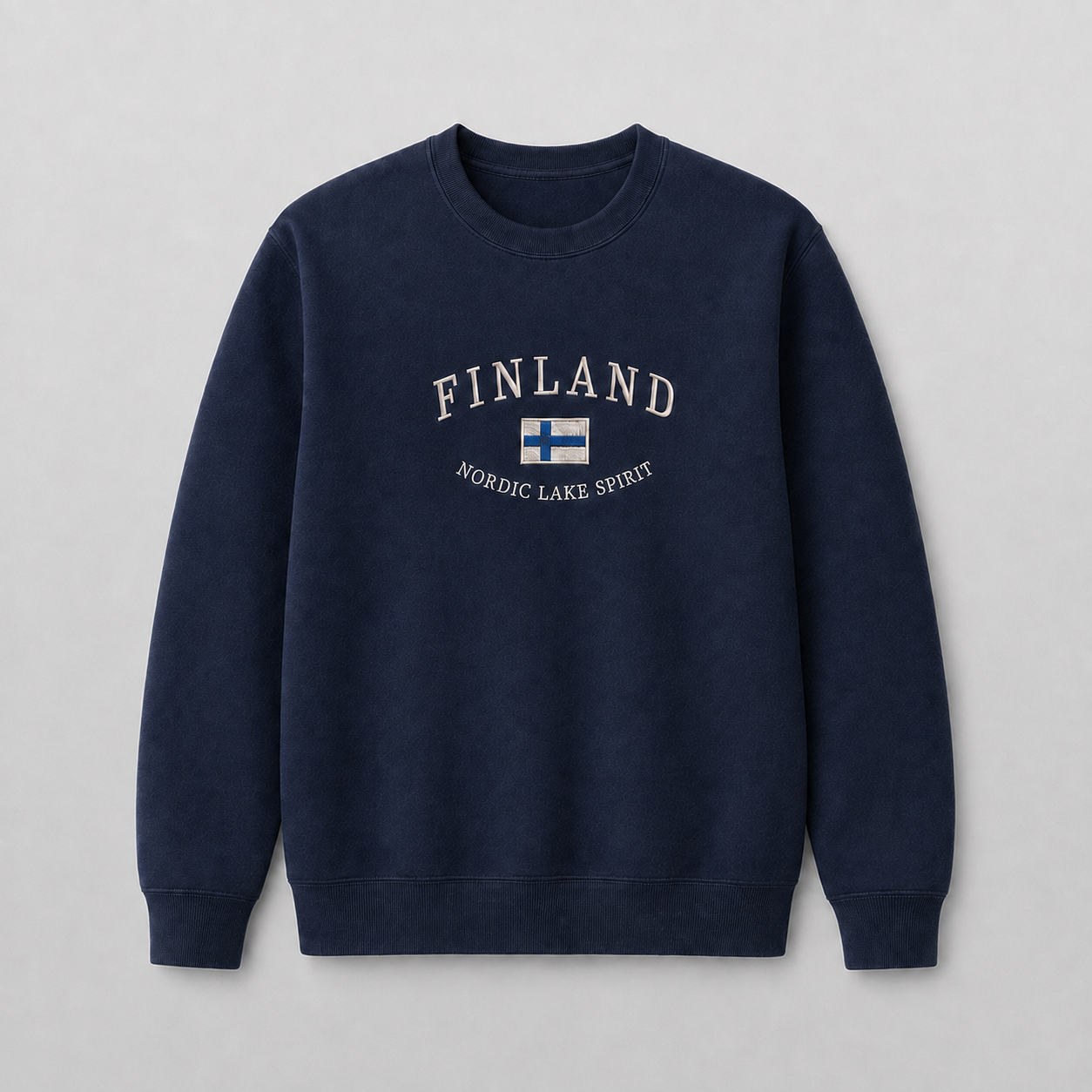 Tummansininen huputon kirjailtu collegepaita harmaalla studiotaustalla, FINLAND-teksti, Suomen lippu ja NORDIC LAKE SPIRIT