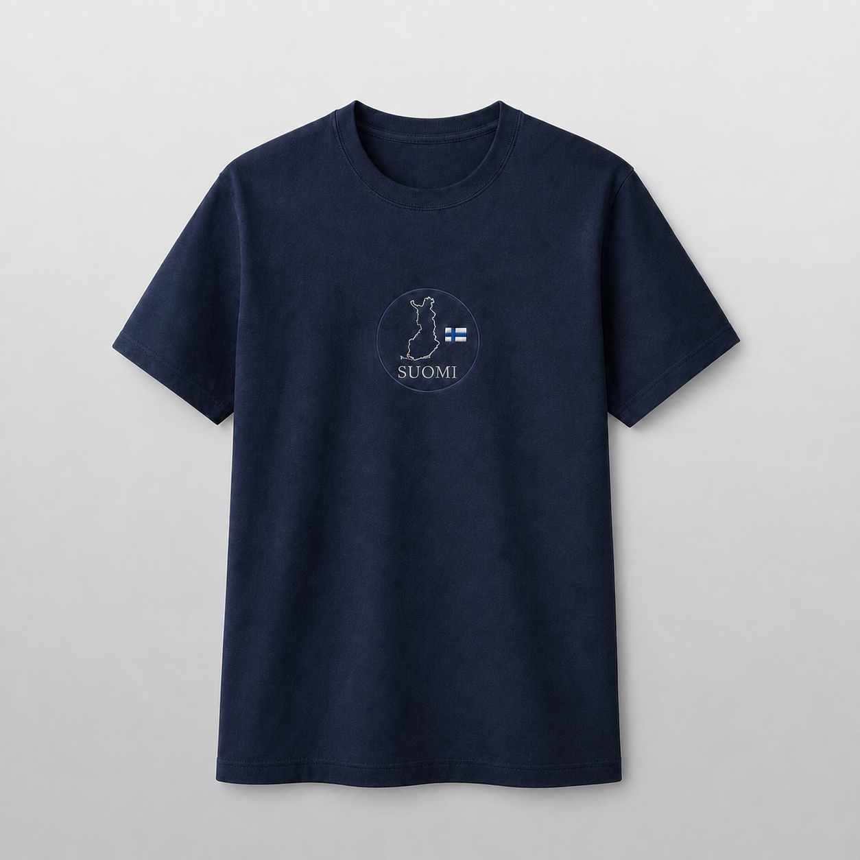 Tummansininen kirjailtu T-paita harmaalla studiotaustalla, pyöreä Suomen kartta, pieni Suomen lippu ja SUOMI-teksti